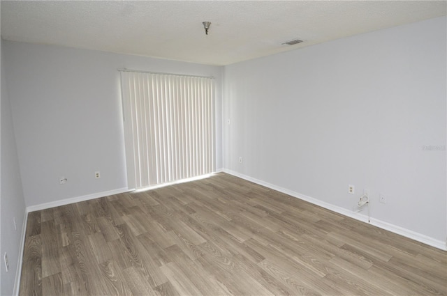 spare room featuring a textured ceiling and light hardwood / wood-style flooring