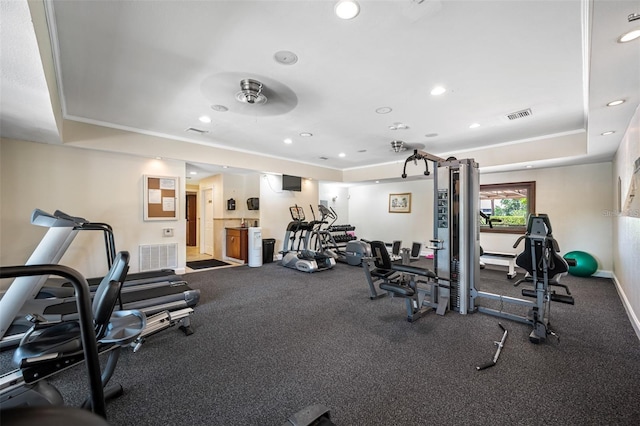 exercise room with a tray ceiling and ceiling fan