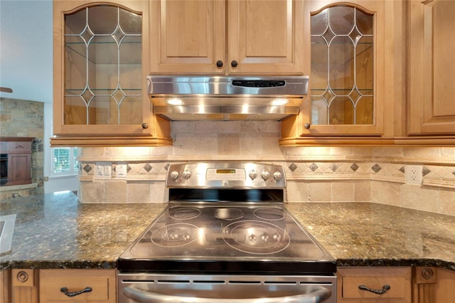 kitchen with stainless steel electric range oven, exhaust hood, backsplash, and dark stone counters