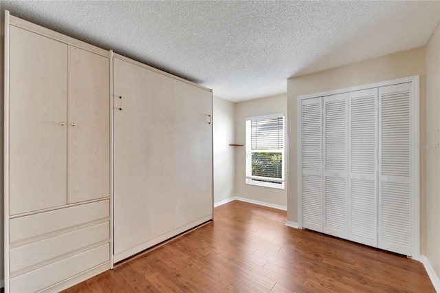 unfurnished bedroom with wood-type flooring and a textured ceiling