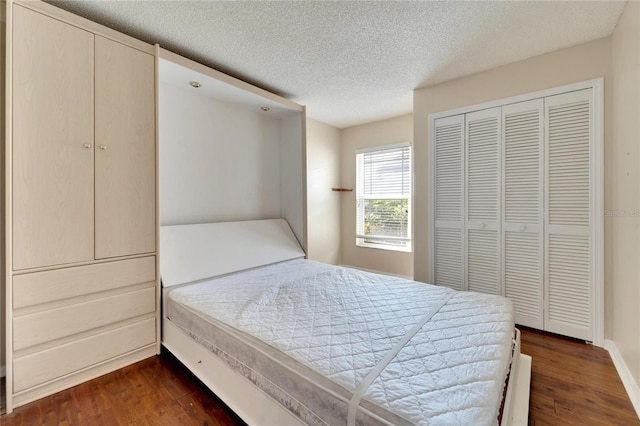 bedroom featuring dark wood-type flooring, a closet, and a textured ceiling