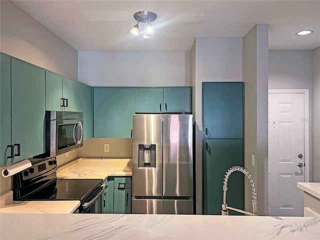 kitchen featuring appliances with stainless steel finishes, light stone counters, and green cabinetry