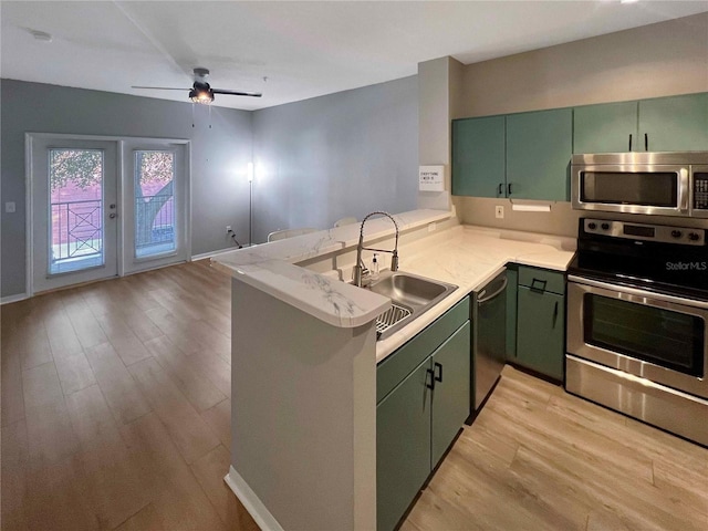 kitchen featuring kitchen peninsula, stainless steel appliances, green cabinetry, and sink