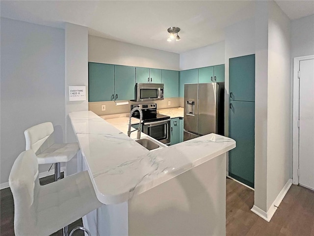 kitchen with sink, stainless steel appliances, a kitchen breakfast bar, dark hardwood / wood-style floors, and kitchen peninsula