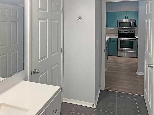 kitchen with blue cabinetry, dark hardwood / wood-style flooring, and appliances with stainless steel finishes