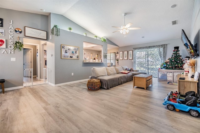 living room featuring a textured ceiling, ceiling fan, lofted ceiling, and light wood-type flooring