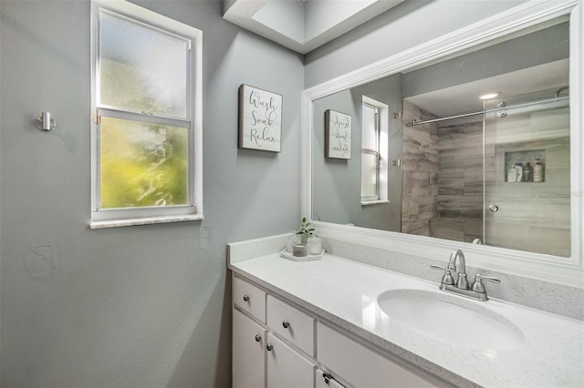 bathroom with a tile shower and vanity