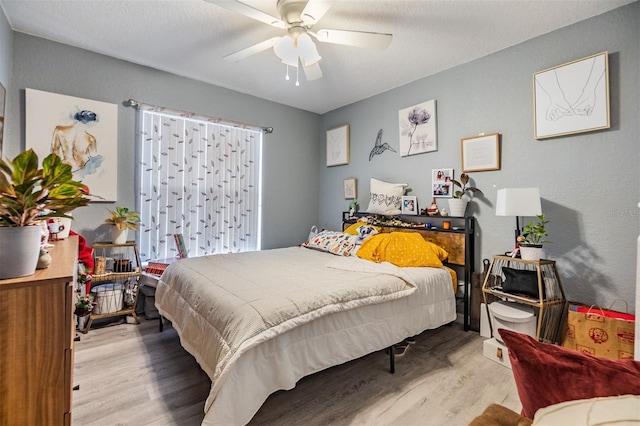 bedroom with a textured ceiling, light wood-type flooring, and ceiling fan