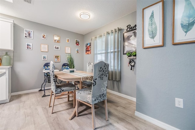 dining room with light hardwood / wood-style flooring and a textured ceiling