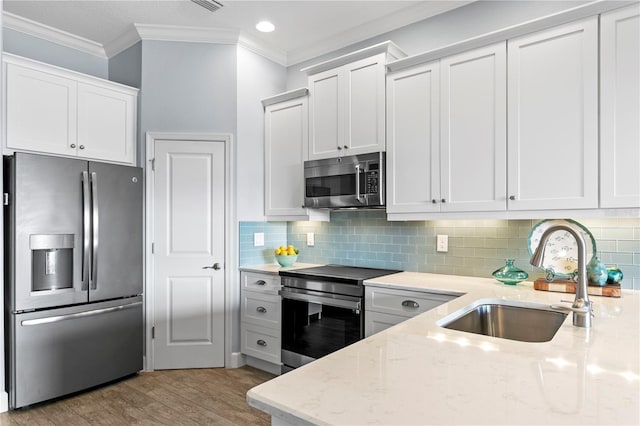 kitchen featuring light stone countertops, light wood-type flooring, stainless steel appliances, sink, and white cabinetry