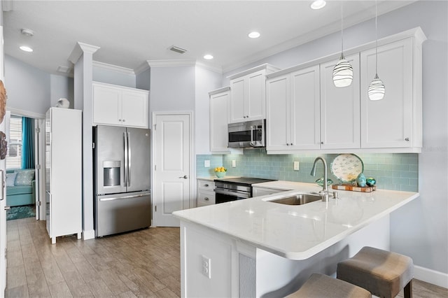 kitchen featuring pendant lighting, stainless steel appliances, white cabinetry, and sink