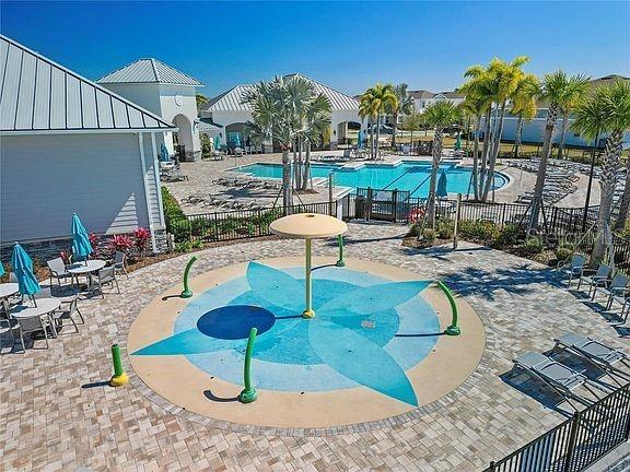 community pool featuring a patio area, fence, and a water play area