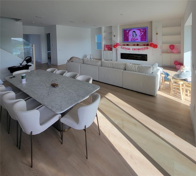 dining room featuring a glass covered fireplace and wood finished floors