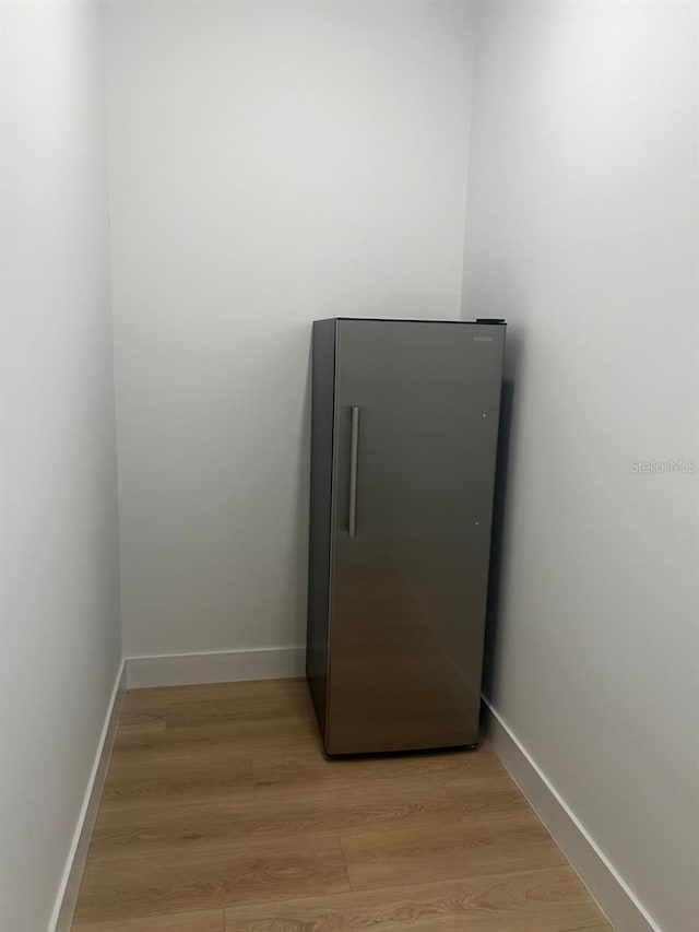 details with baseboards, high end fridge, and wood finished floors