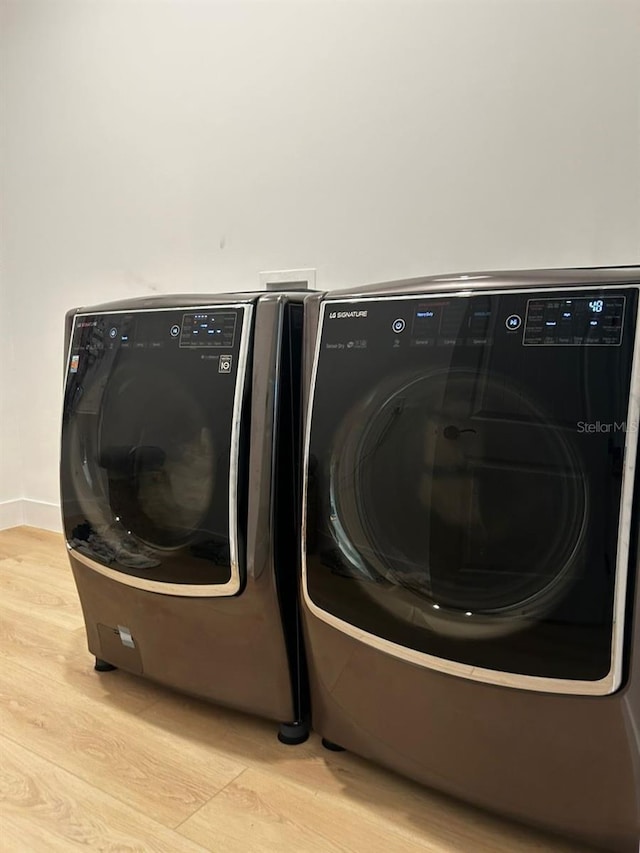 clothes washing area featuring light wood-type flooring and independent washer and dryer