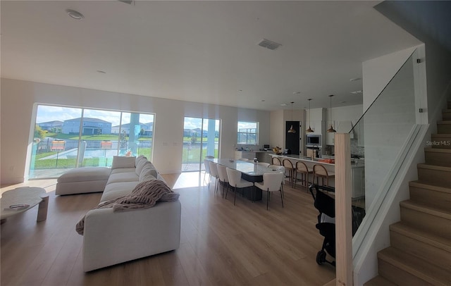 living room featuring light wood-style floors, visible vents, and stairway