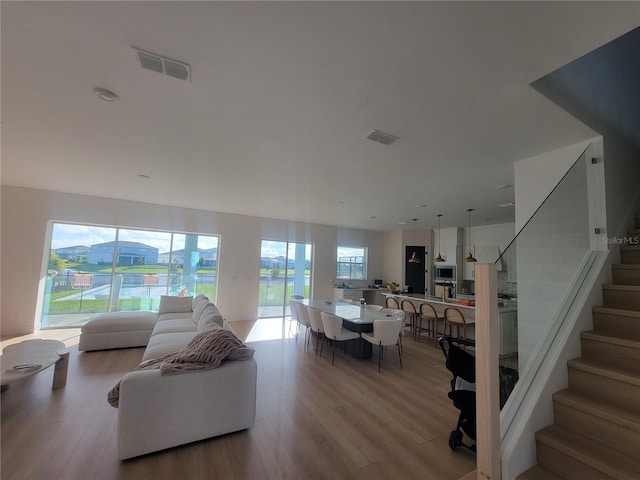 living area with visible vents, light wood-style flooring, and stairs