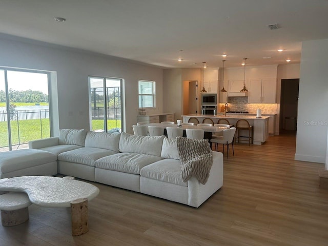 living room featuring a healthy amount of sunlight, light wood-style floors, visible vents, and recessed lighting