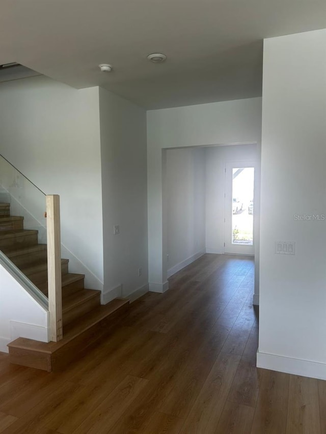 interior space featuring baseboards, hardwood / wood-style floors, and stairs