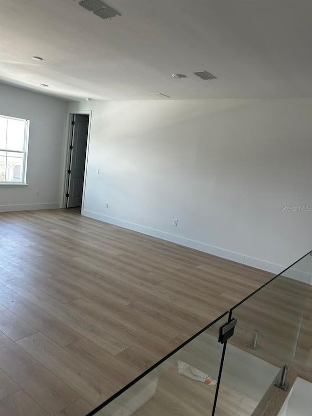 unfurnished room featuring visible vents, baseboards, and wood finished floors