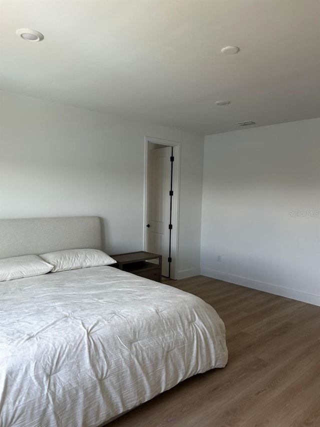 bedroom with visible vents, baseboards, and wood finished floors