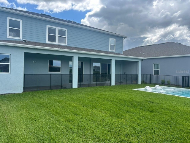 rear view of property with stucco siding, a yard, and fence