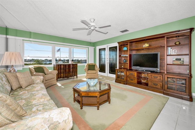 living room featuring a textured ceiling, light tile patterned floors, visible vents, and a ceiling fan