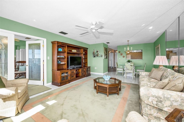 living room featuring light carpet, baseboards, visible vents, and ceiling fan with notable chandelier