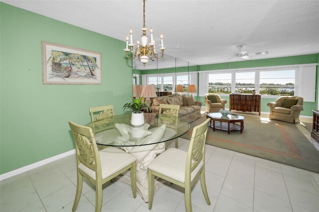 dining area with light tile patterned flooring, a textured ceiling, baseboards, and ceiling fan with notable chandelier