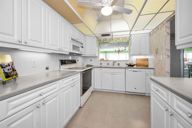 kitchen featuring white appliances, white cabinets, light countertops, a sink, and light tile patterned flooring