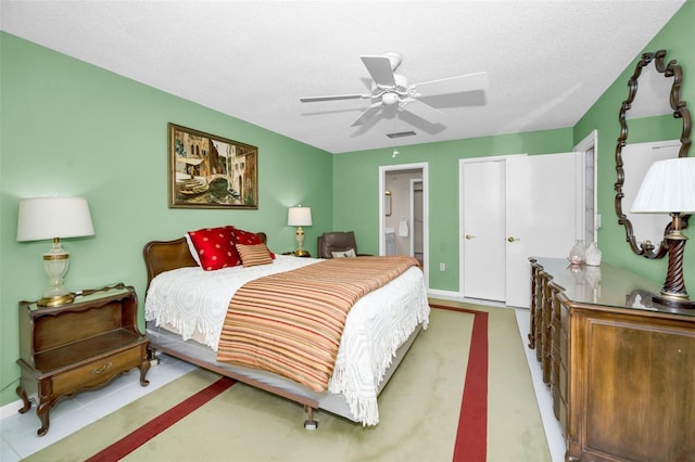 bedroom with ensuite bath, ceiling fan, and a textured ceiling