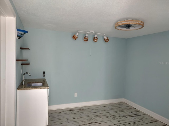 unfurnished dining area featuring a textured ceiling and sink