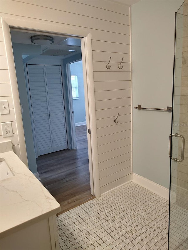 bathroom featuring hardwood / wood-style floors, vanity, an enclosed shower, and wooden walls