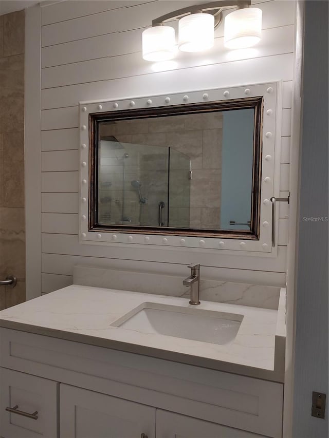 bathroom featuring vanity, wood walls, and a shower with door