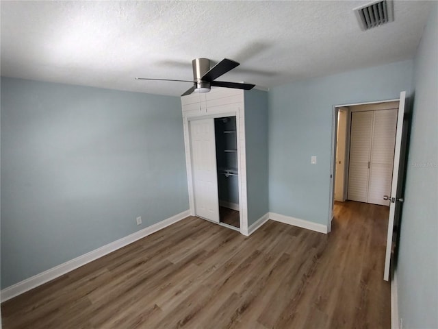 unfurnished bedroom featuring a textured ceiling, dark hardwood / wood-style flooring, a closet, and ceiling fan