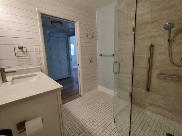 bathroom with tile patterned flooring, vanity, wood walls, and a shower with shower door