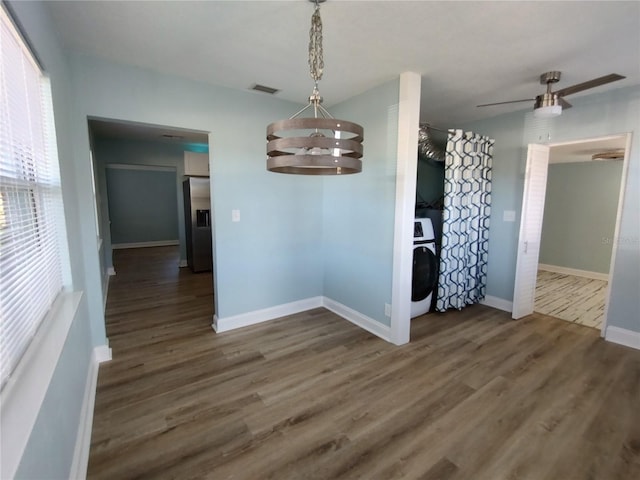 unfurnished dining area with washer / dryer, ceiling fan with notable chandelier, and dark hardwood / wood-style floors