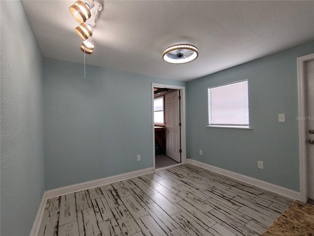 empty room featuring a textured ceiling and light hardwood / wood-style floors