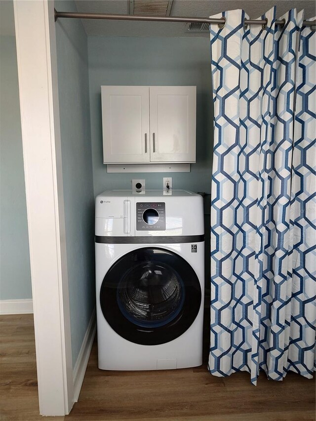 clothes washing area with dark wood-type flooring, cabinets, and washer / dryer