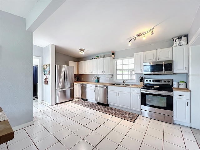 kitchen featuring white cabinets, light tile patterned floors, stainless steel appliances, and sink