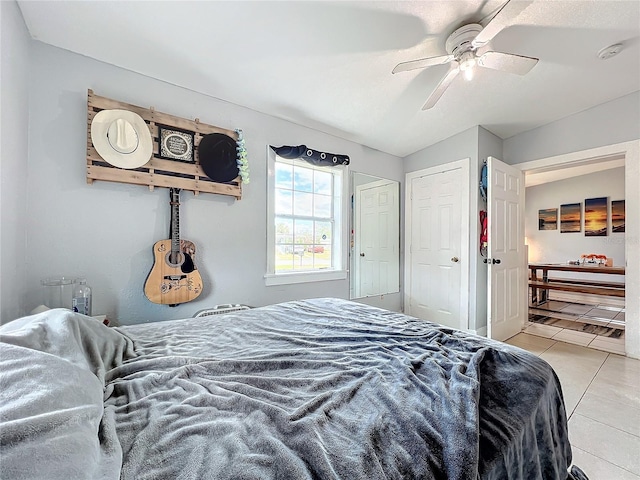 bedroom featuring ceiling fan, light tile patterned floors, and vaulted ceiling