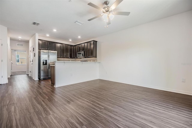 kitchen featuring ceiling fan, dark hardwood / wood-style flooring, kitchen peninsula, a kitchen bar, and appliances with stainless steel finishes