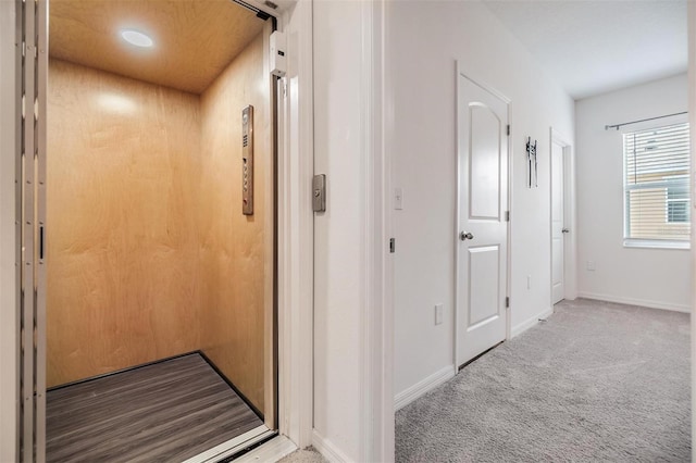 hallway with light colored carpet and elevator