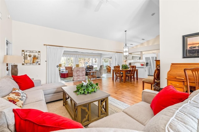 living room featuring ceiling fan, vaulted ceiling, and light wood-type flooring