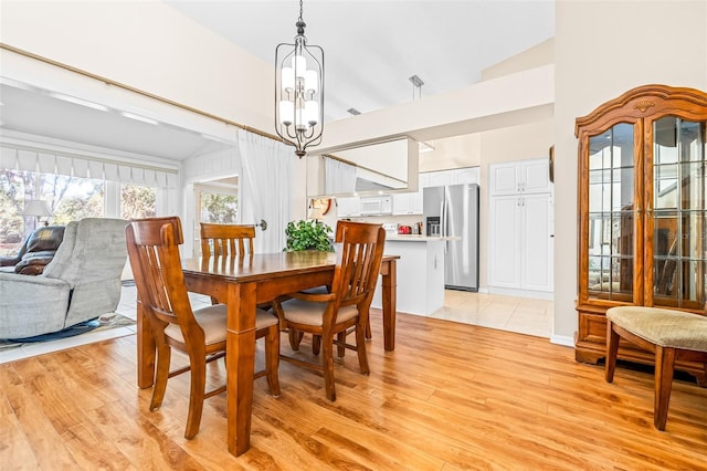 dining room with a chandelier, light hardwood / wood-style floors, and lofted ceiling