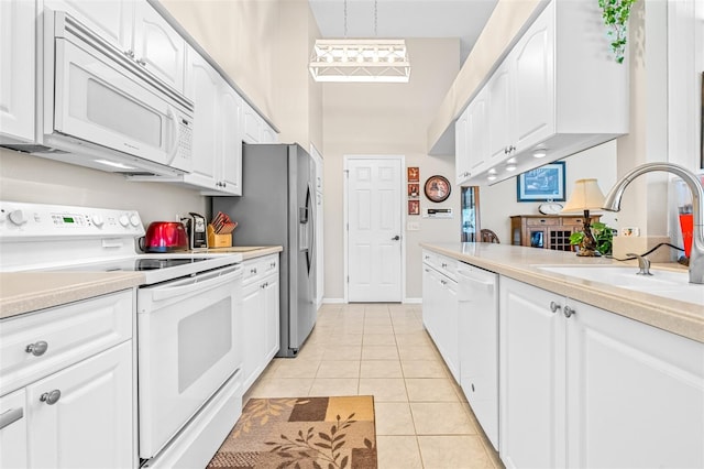 kitchen with white appliances, sink, pendant lighting, light tile patterned floors, and white cabinetry