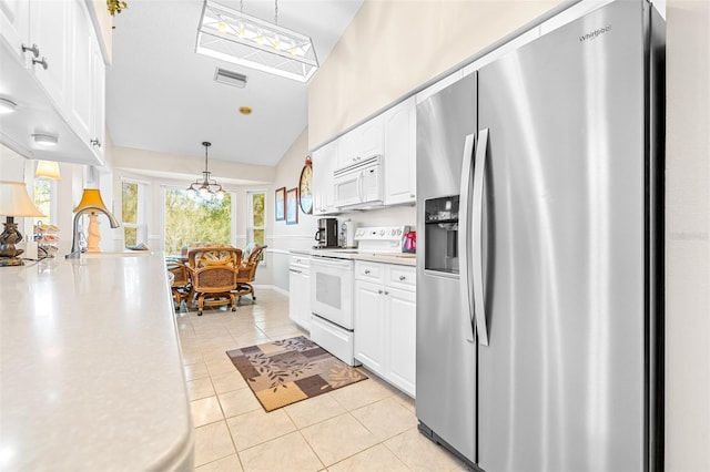 kitchen featuring white appliances, vaulted ceiling, light tile patterned floors, decorative light fixtures, and white cabinetry