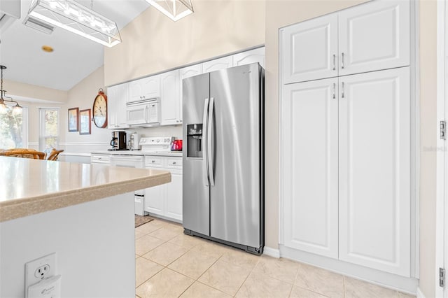 kitchen with pendant lighting, white appliances, vaulted ceiling, light tile patterned floors, and white cabinetry