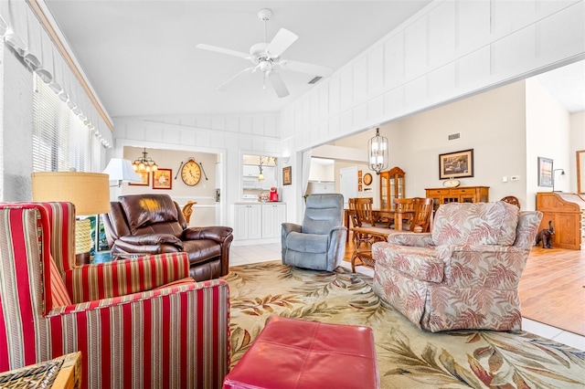 living room with wood-type flooring, ceiling fan with notable chandelier, and lofted ceiling