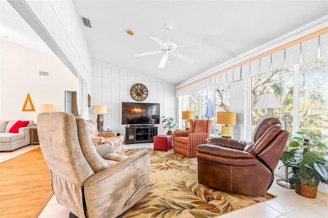 living room featuring wooden walls, light hardwood / wood-style floors, ceiling fan, and lofted ceiling